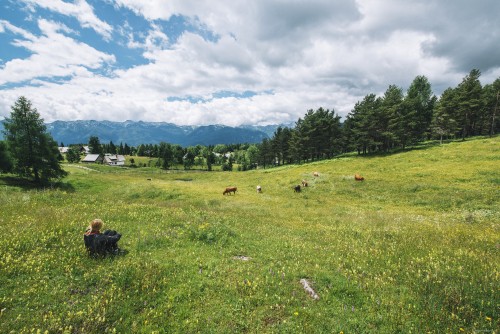 Woman hiker resting on a Sunny and cloudy day in the meadows surrounded by forest and mountains